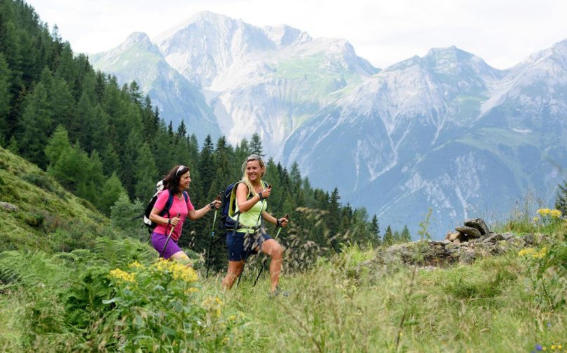 Freundinnen beim Wandern durch eine Almwiese in St. Anton am Arlberg